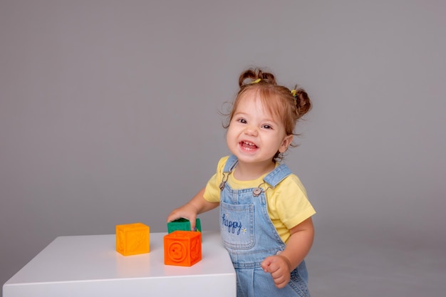 pequeña niña sobre un fondo blanco y jugando con cubos de colores. juguete para niños cu