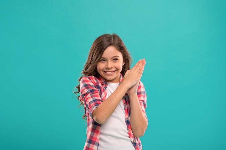 Foto pequeña niña sonríe emocionada con una nueva idea de pie sobre fondo azul este es el punto solución de la idea niña linda cara alegre descubrió una idea importante pequeña niña de pelo largo tiene una idea brillante