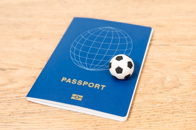 pequeña pelota de fútbol de juguete y pasaporte biométrico en una mesa de madera