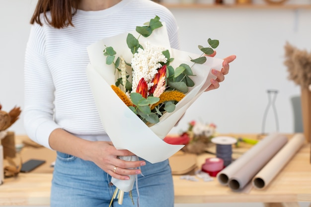 Foto pequeña persona emprendedora y ramo de flores