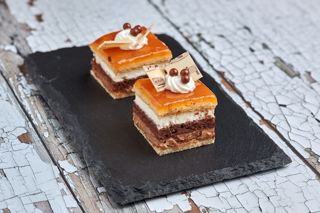 Pequeña porción de un pastel típico español conocido como postre de San Marcos en una placa de pizarra negra sobre una mesa antigua.