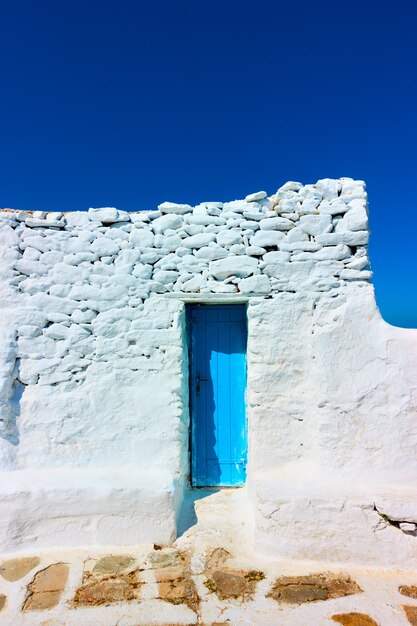 Pequena porta azul estreita em uma antiga parede caiada de branco, Mykonos, Grécia