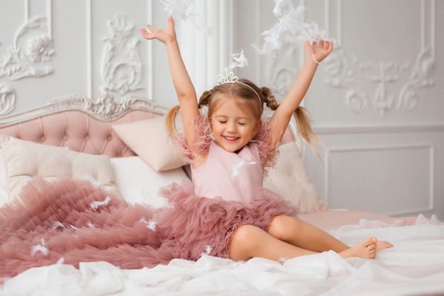 pequeña princesa en un vestido de noche está acostada en una hermosa cama