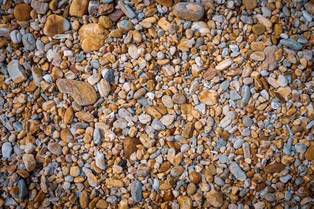 Pequeña roca en la textura del fondo del tono del color del marrón de la playa.