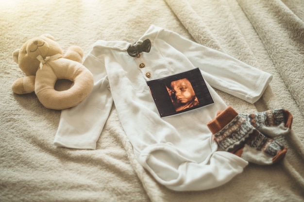 Pequeña ropa de bebé hecha a mano. Foto de ultrasonido. ropa de recién nacido. Unidad, protección y felicidad