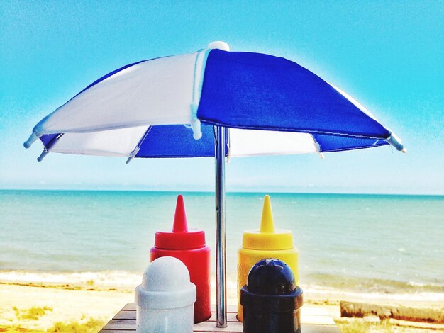 Foto pequeña sombrilla sobre botellas en la mesa en la playa