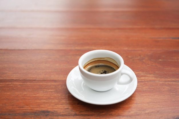 pequeña taza de café blanca en una mesa de madera roja