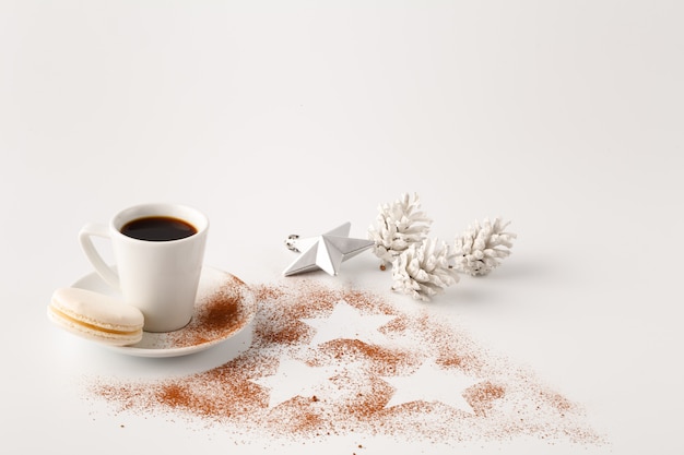 Una pequeña taza de café y cacao en polvo sobre la mesa blanca