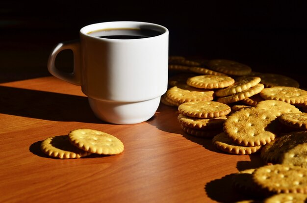 Pequeña taza de café y galleta salada.