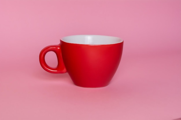 Pequeña taza de café roja sobre un fondo rosa