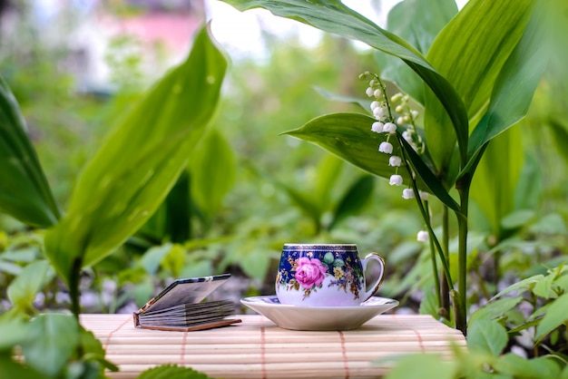 Una pequeña taza de té junto a las flores de lirios del valle.