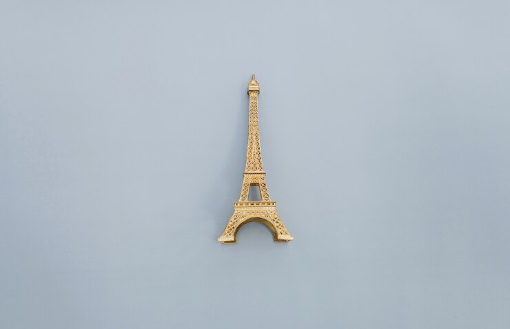 Foto la pequeña torre eiffel como recuerdo de parís sobre un fondo gris.