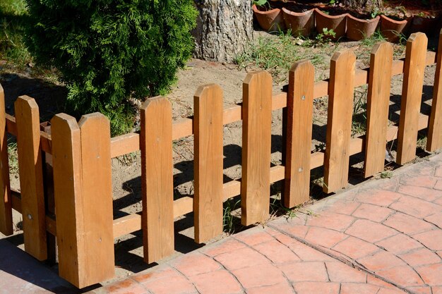 Pequeña valla de madera cerca de thuja en un día soleado al aire libre