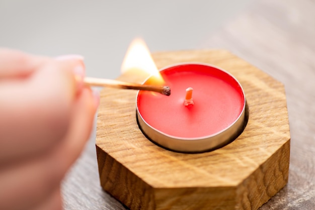 Pequeña vela roja en candelabro de madera sobre la mesa de cerca