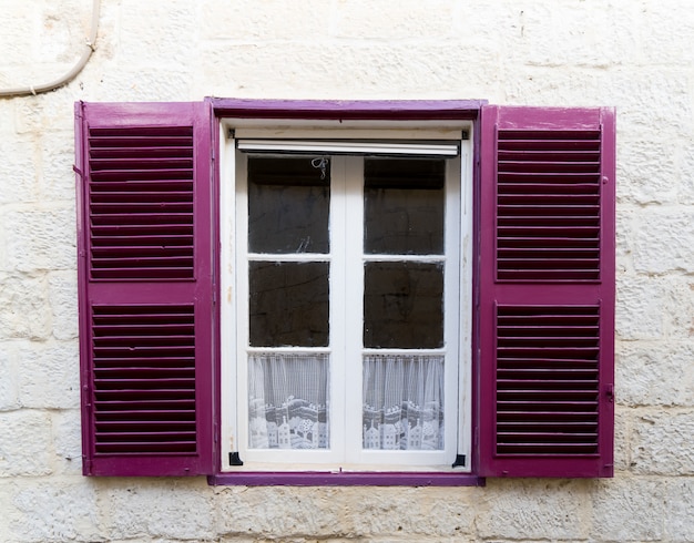 Pequeña ventana con persianas de color púrpura.