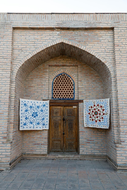 Pequeñas alfombras cuelgan de la pared frente a la entrada de la tienda de souvenirs en Samarcanda, Uzbekistán