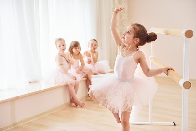 Pequenas bailarinas em uniformes rosa, preparando-se para o desempenho