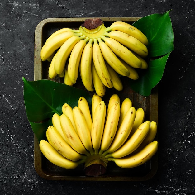 Pequenas bananas tropicais Conjunto de bananas Em um fundo de pedra preta Espaço para cópia grátis