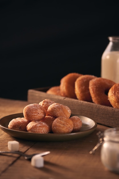 Pequeñas bolas de donuts de requesón caseros recién horneados en una placa sobre un fondo gris.