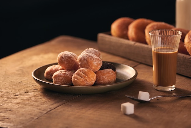 Pequeñas bolas de donuts de requesón caseros recién horneados en una placa sobre un fondo gris.