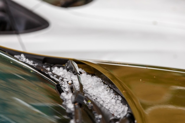 Pequeñas bolas de hielo de granizo en el capó del coche marrón después de una fuerte tormenta de verano