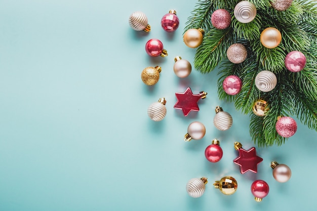 Pequeñas bolas navideñas rosadas y doradas y rama de árbol de navidad