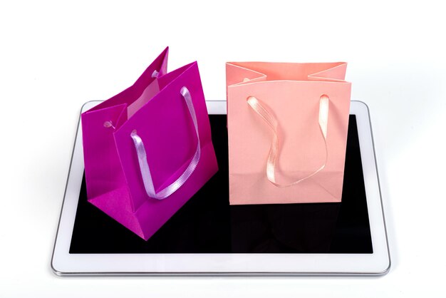 pequeñas bolsas de compras coloridas en una tableta moderna contra un fondo blanco concepto de comercio electrónico