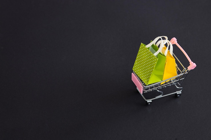 Foto pequeñas bolsas de papel con carrito de compras sobre fondo negro