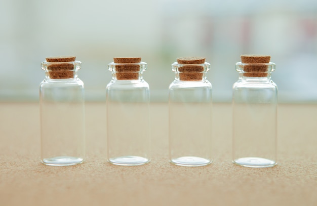 Foto pequeñas botellas vacías con tapón de corcho, sobre fondo borroso
