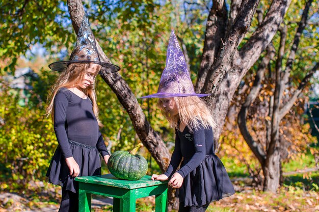 Pequeñas brujas adorables se divierten al aire libre en Halloween. Truco o trato.