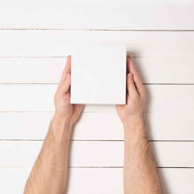 Pequeñas cajas de cartón blanco en manos masculinas. Vista superior.