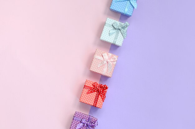 Pequeñas cajas de regalo de diferentes colores con listones en violeta y rosa.