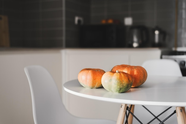 Pequeñas calabazas en una mesa de comedor blanca de pie en el área de la cocina