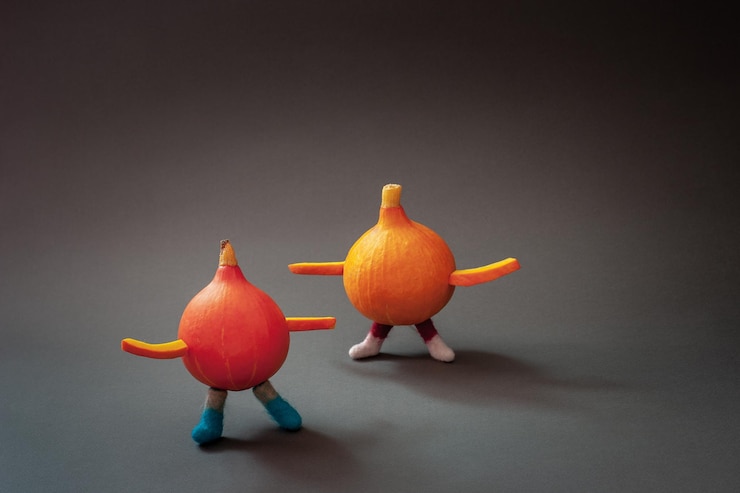 Foto pequeñas calabazas rojas y naranjas con brazos y piernas paradas cerca figuras divertidas sobre un fondo gris espacio de copia viñeta