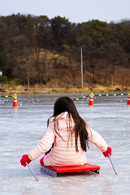 Pequenas crianças andando de trenó de gelo no lago congelado