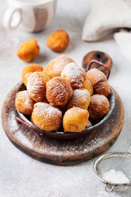 Pequeñas donas. Galletas fritas de cuajada casera en grasa profunda y espolvoreadas con azúcar glas en un plato vintage