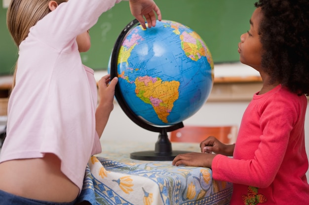 Foto pequenas estudantes pequenas olhando um globo