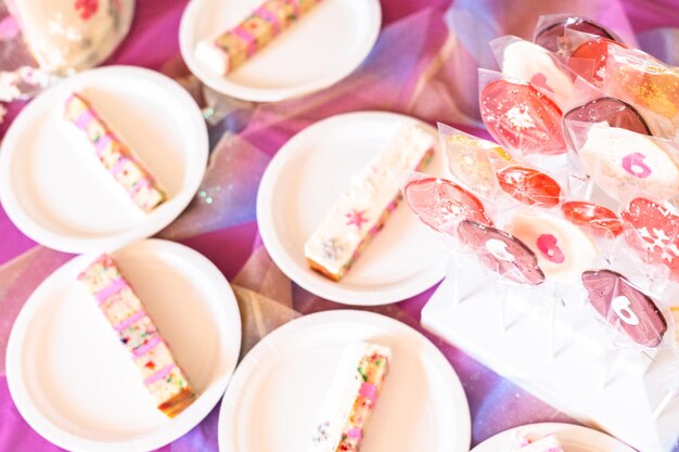 Pequenas fatias de bolo de aniversário em placas de papel branco.