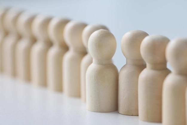 Pequeñas figuritas de madera colocadas en fila larga sobre una mesa blanca figura de persona blanca hecha de soportes de madera