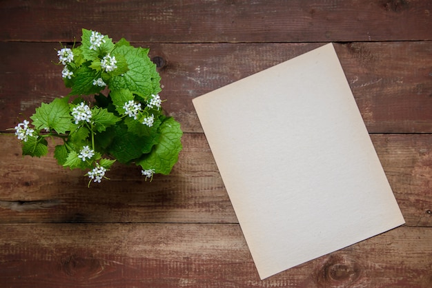 Pequeñas flores blancas sobre un fondo de madera con hoja de papel con espacio de copia