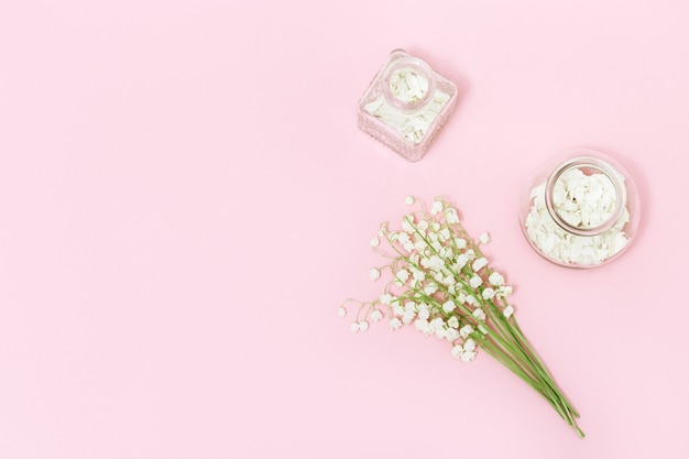 Pequeñas flores y botella de vidrio con pétalos secos como aromaterapia spa