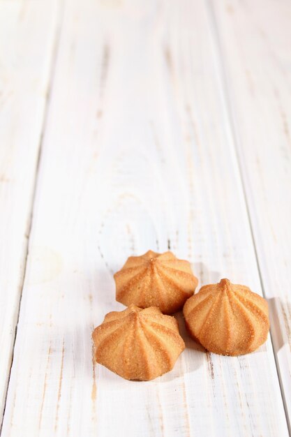 Pequeñas y hermosas galletas marrones en un fondo de mesa de madera blanca