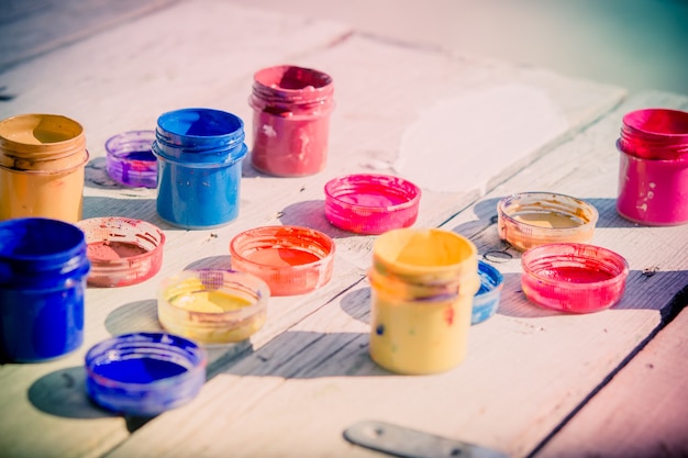 Pequeñas latas de pintura gouache pararse sobre una mesa de madera