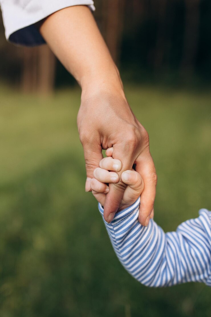 Foto pequenas mãos de uma criança segurando o dedo de sua mãe apoio parental cuidados e amor parentais