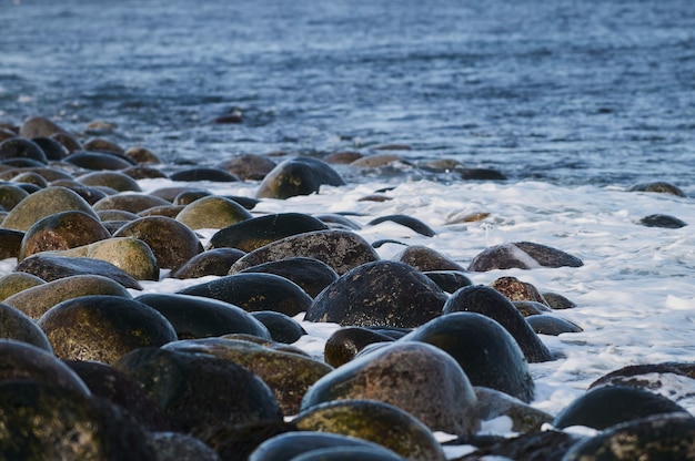 Pequeñas olas del mar rompen contra las piedras de la orilla.