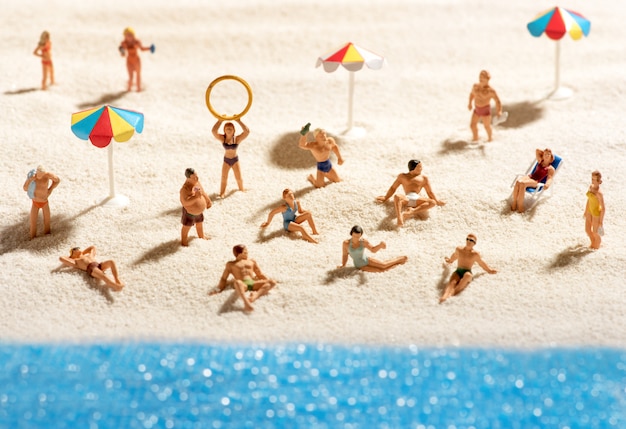 Pequenas pessoas em miniatura, banhos de sol na praia