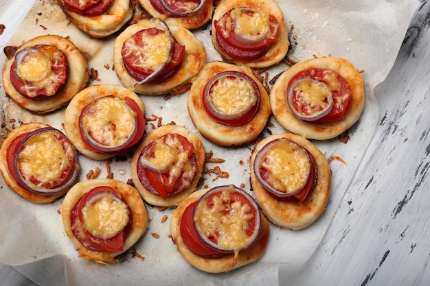 Pequenas pizzas em papel manteiga de perto