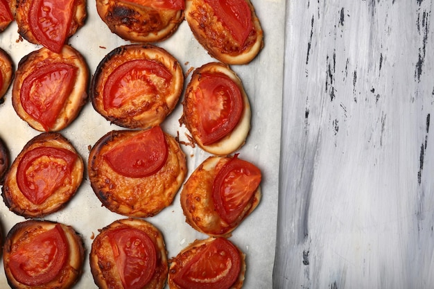 Pequenas pizzas em papel manteiga de perto