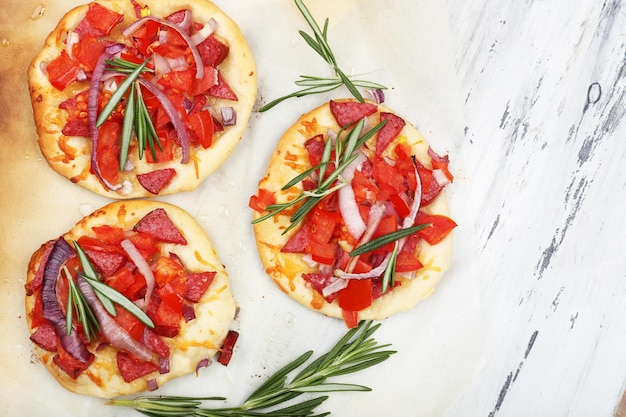 Pequeñas pizzas en papel para hornear de cerca