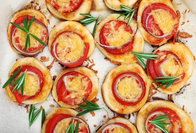 Pequeñas pizzas en papel para hornear de cerca